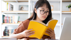 Vrouw aan het dtuderen. ze heeft ene bril op en leest een boek: zelfstudie
